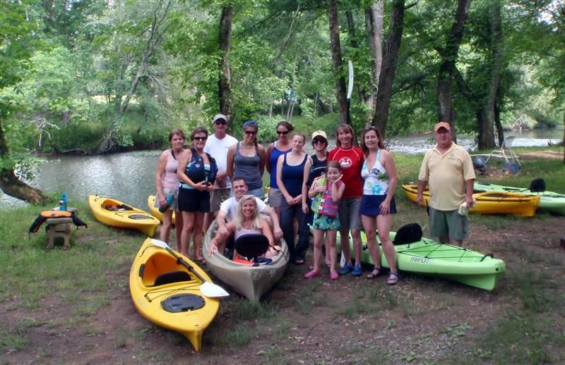 a group of people are posing for a picture in front of kayaks .
