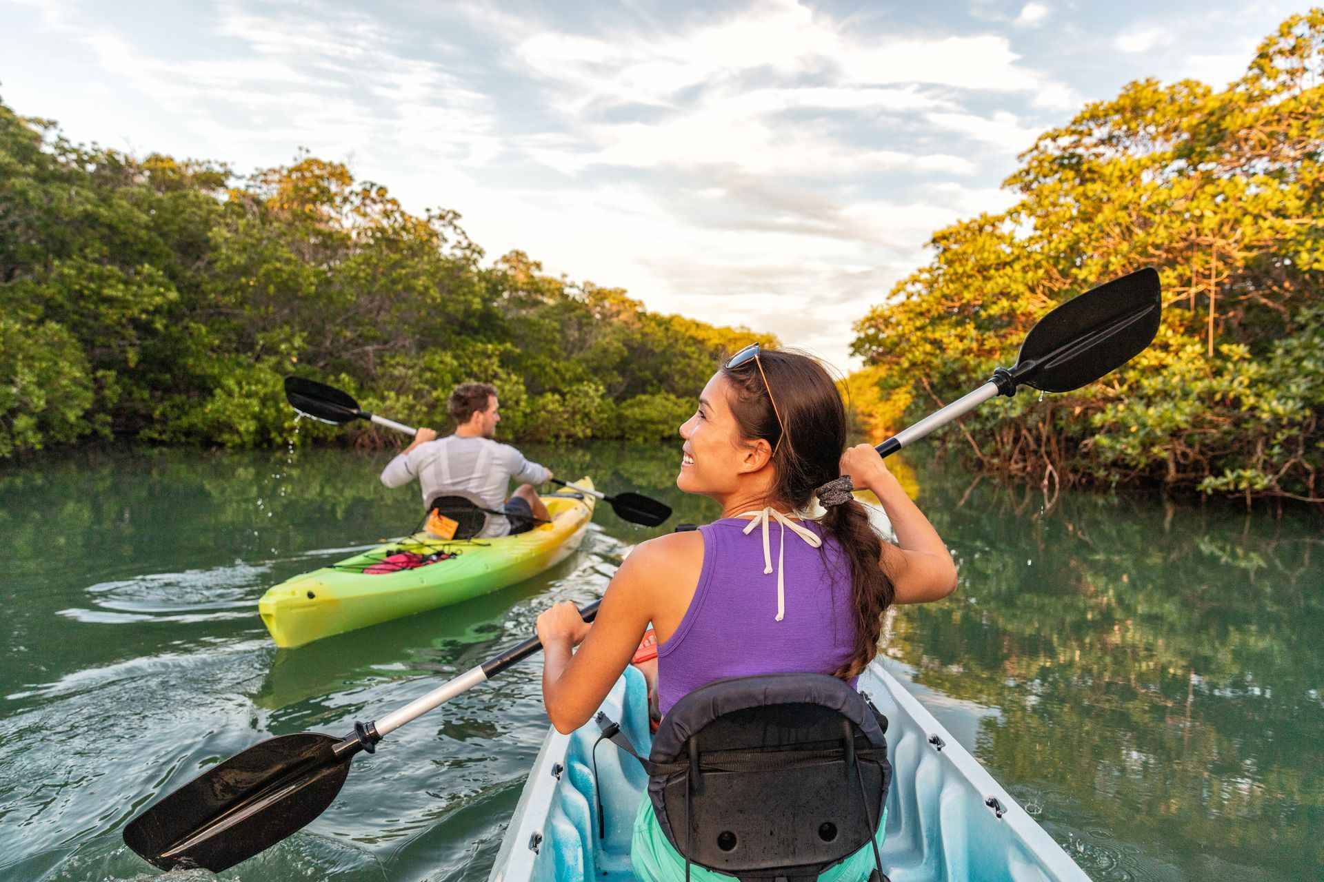 a man and a woman are paddling kayaks on a river .