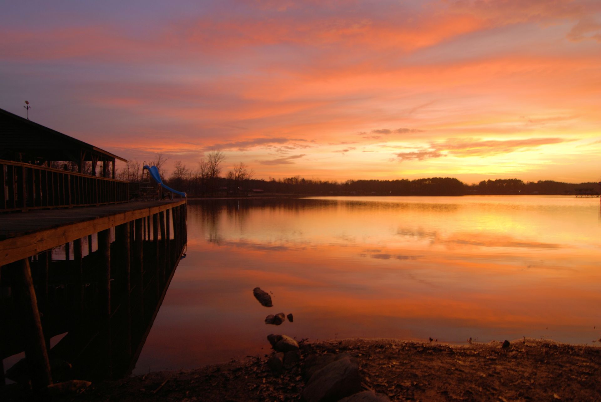 a sunset over a lake with a dock in the foreground .
