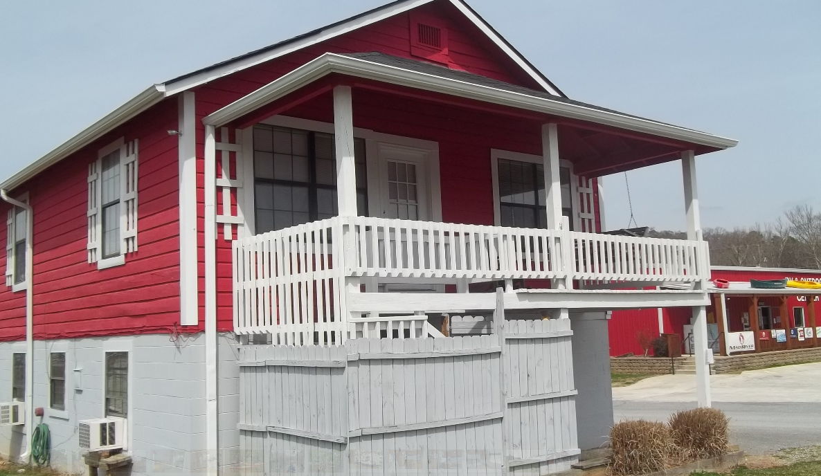 a red house with a white porch and a white fence