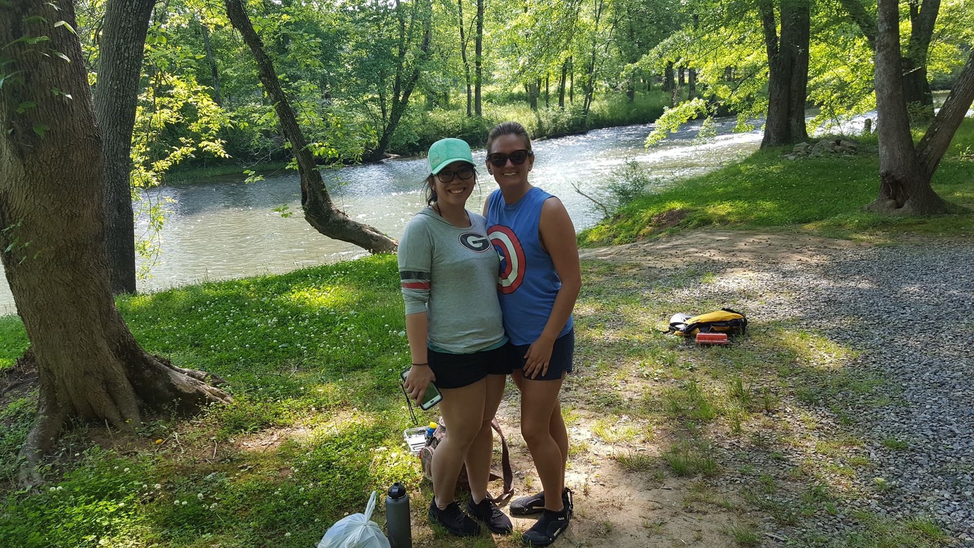 two women are standing next to each other in front of a river .