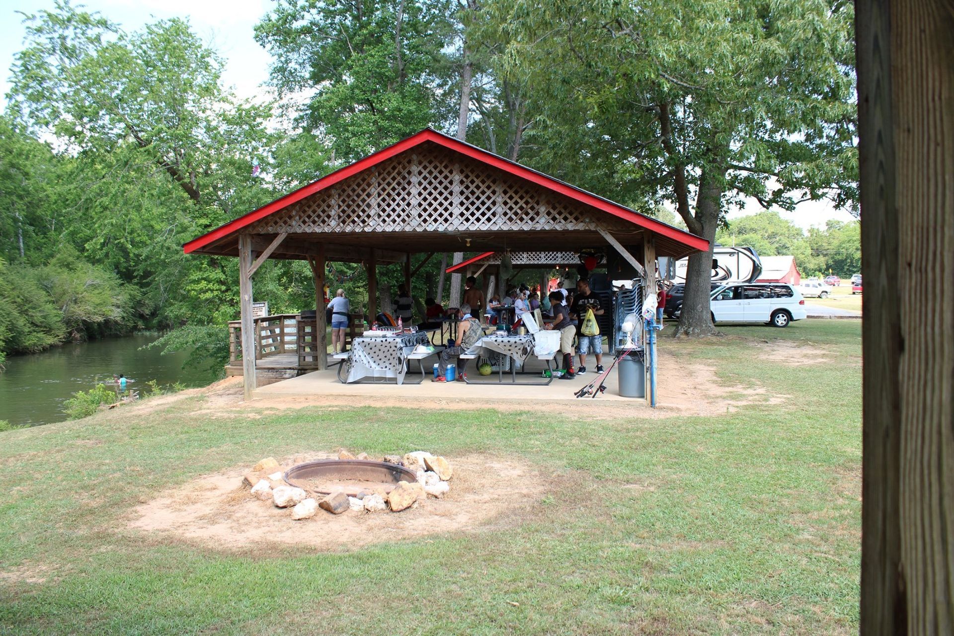 a group of people are sitting under a pavilion with a fire pit in front of it .