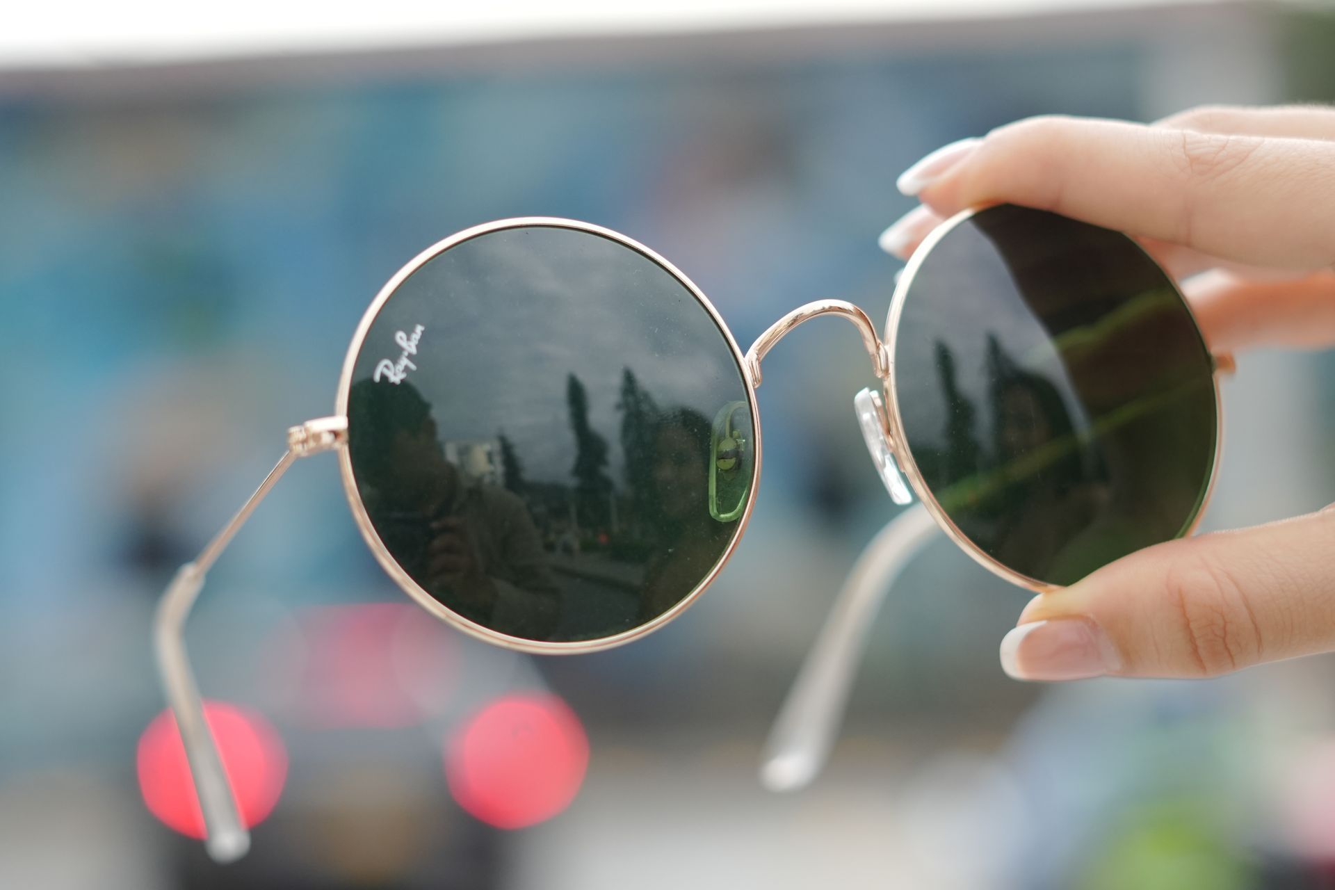 Una persona sostiene un par de gafas de sol redondas Ray-Ban.