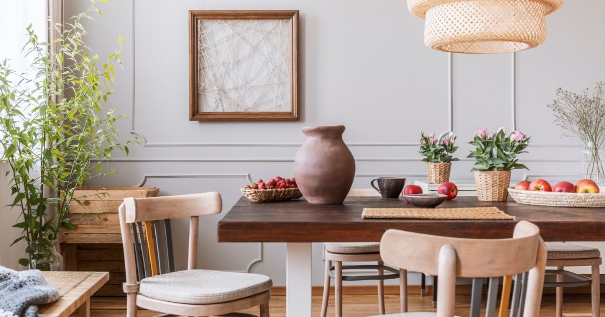 A dining room has a dark wooden table with baskets of fruits and flowers.