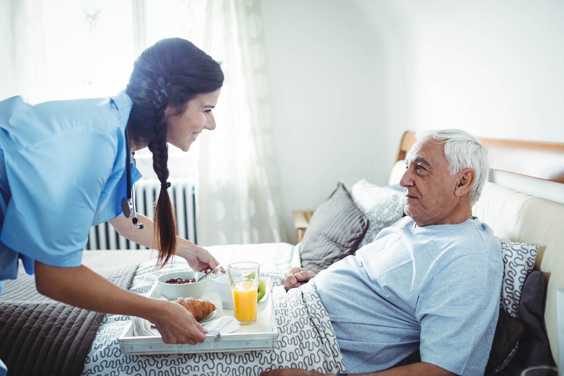 A caregiver is serving breakfast to a senior man. A caregiver is serving breakfast to a senior man.