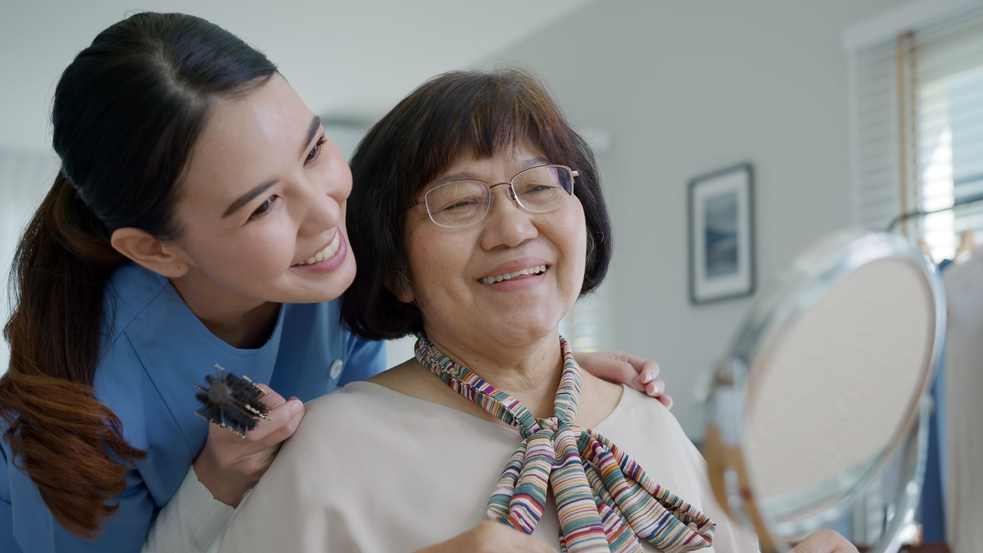 A caregiver helping a senior at home with warm, happy support.