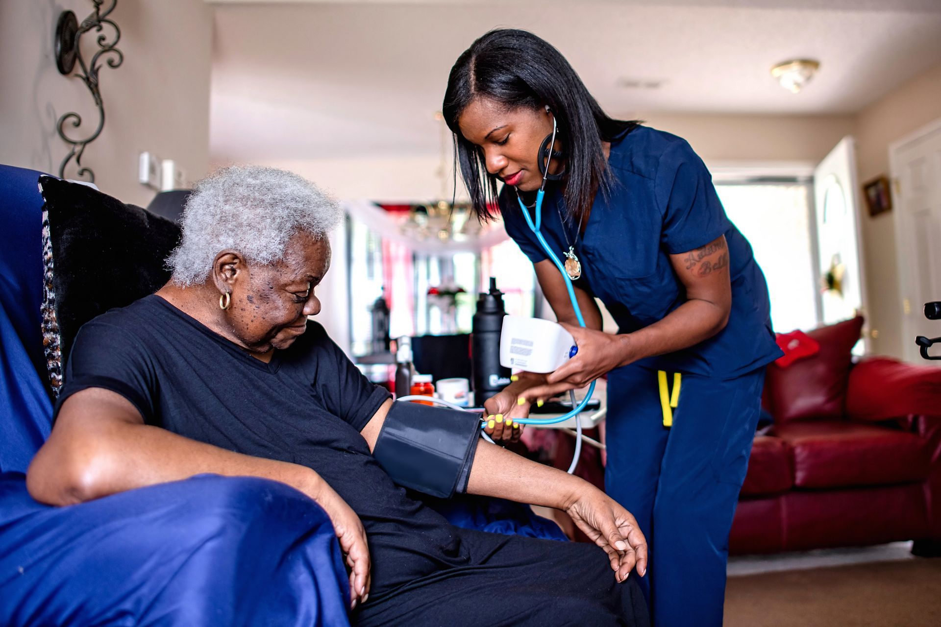 Healthcare worker checks senior’s blood pressure during an in-home medical visit.