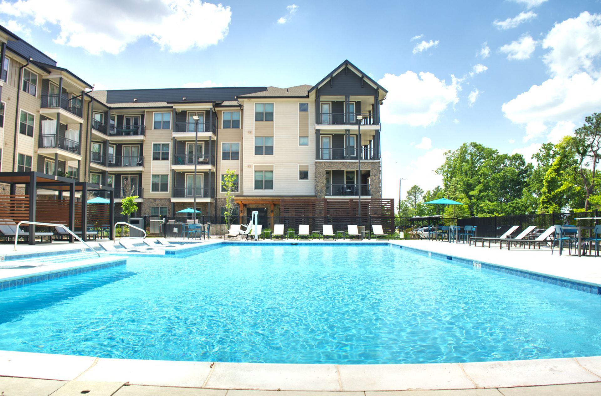 Apartment complex pool with bright blue water and lounge chairs on a sunny day