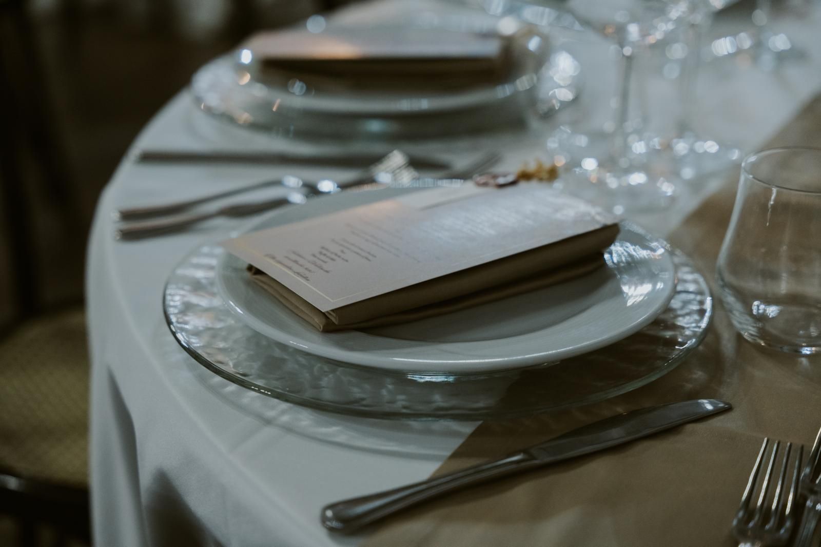 Centrotavola con luci bianche, ciottoli e codice QR in vasi di vetro su un tavolo decorato.