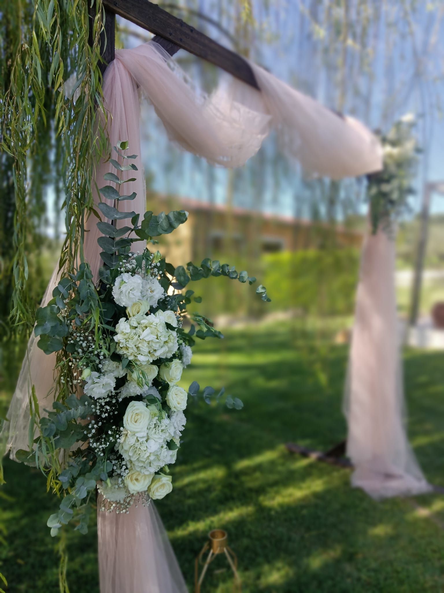 Apparecchiatura per il ricevimento di nozze con bicchieri, piatti e centrotavola floreale.