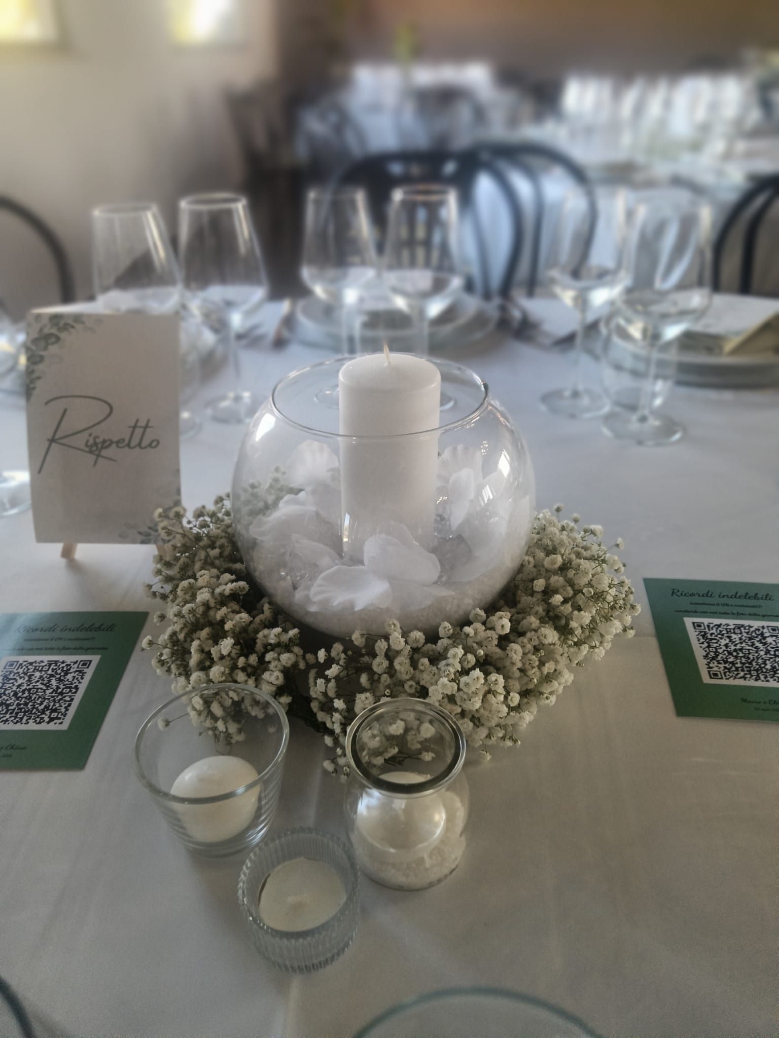 Apparecchiatura della tavola con un centrotavola con candele, piccoli contenitori di vetro e segnaposto.