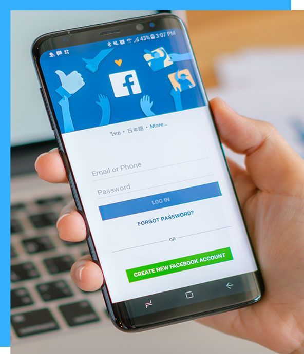 A person is holding a cell phone with the facebook app open.