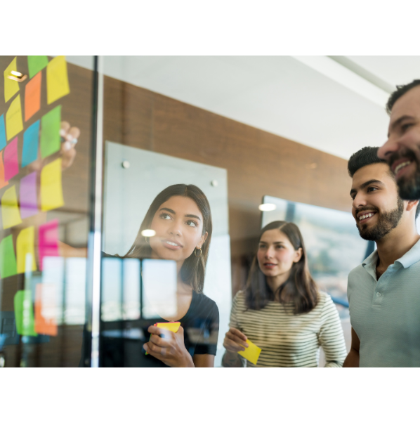 A group of people are looking at sticky notes on a glass wall.