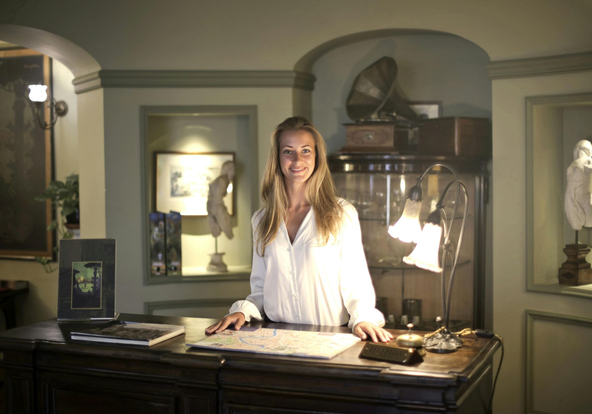 A woman is standing at a reception desk in a hotel.