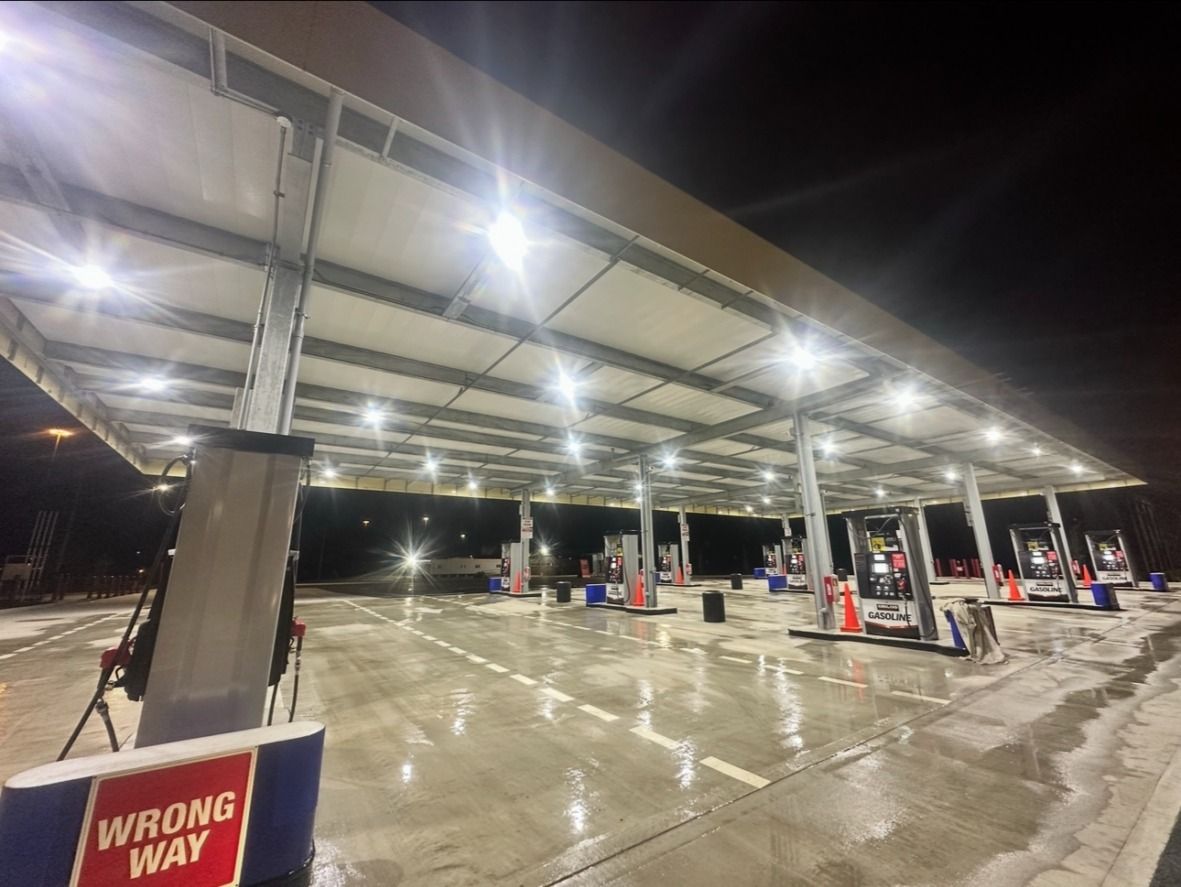 Gas station at night, illuminated by overhead lights, fuel pumps, 