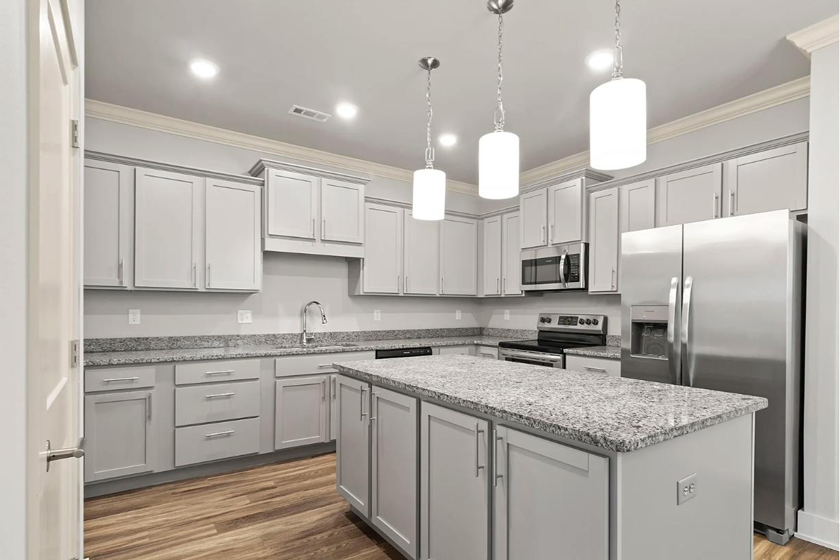 Gray kitchen with granite countertops, island, and stainless steel appliances.