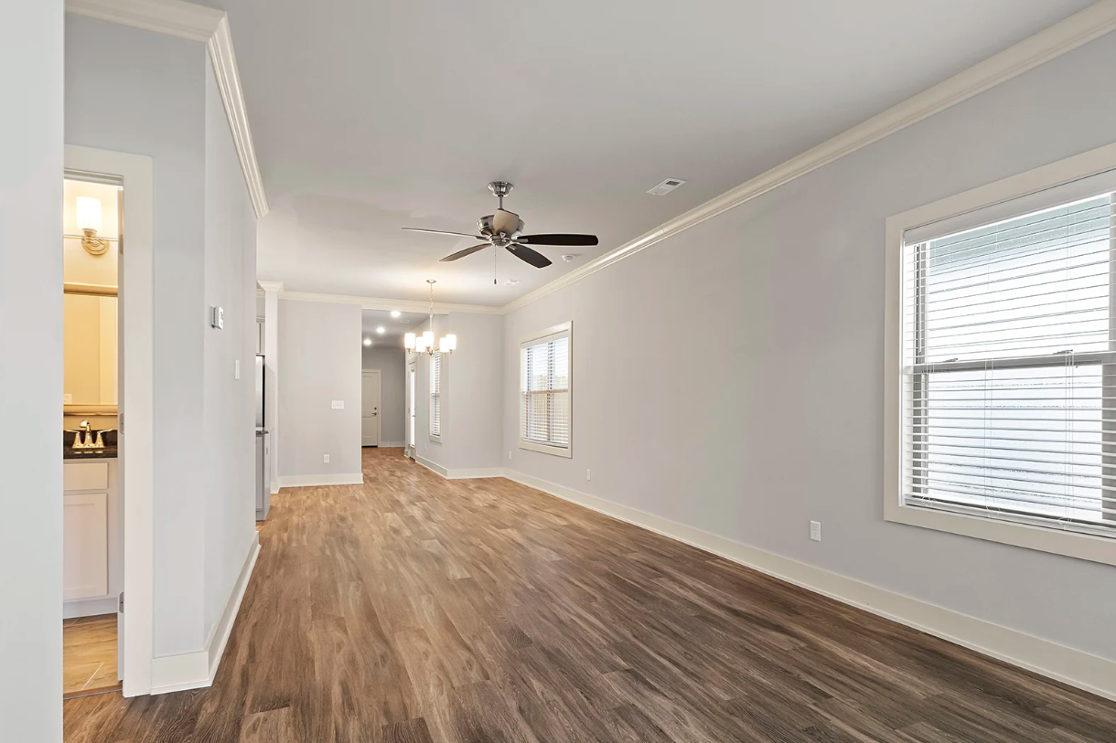 Empty room with wood floors, light blue walls, white trim, and a ceiling fan.