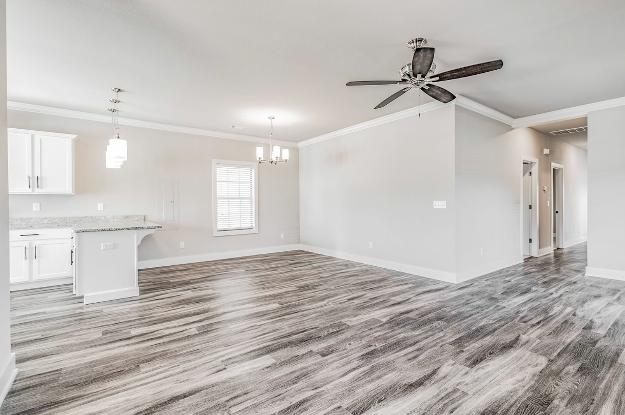 Bright open-concept living space with gray wood-look floors, white cabinets, and a ceiling fan.