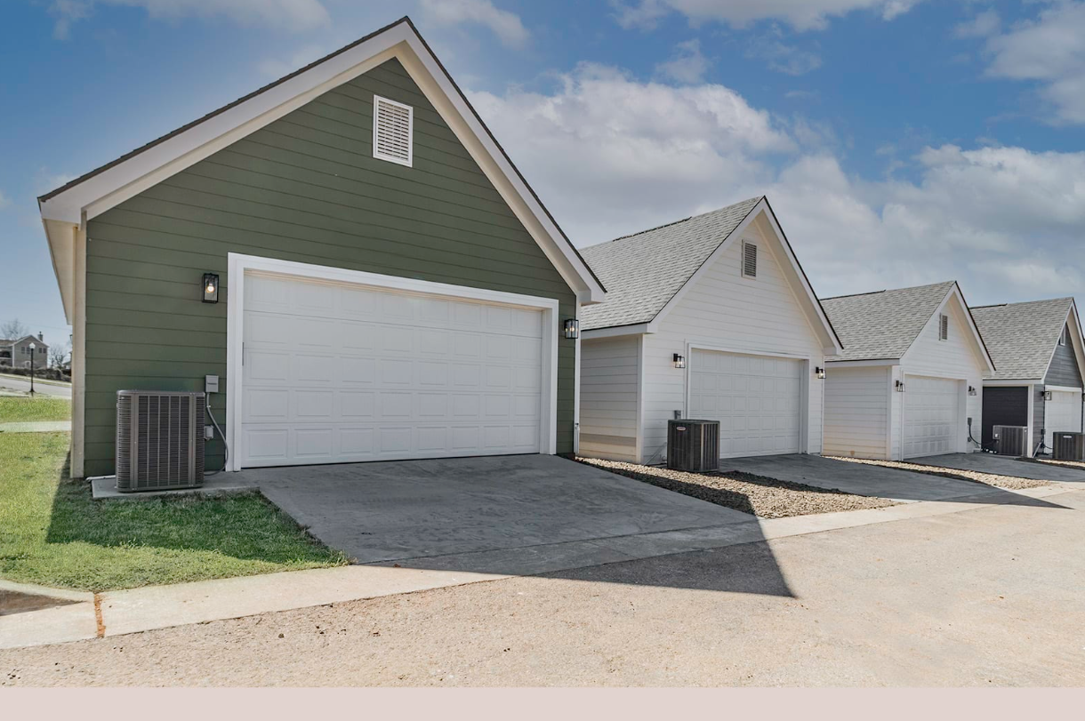 Row of detached garages with white doors and gray roofs, under a partly cloudy blue sky.