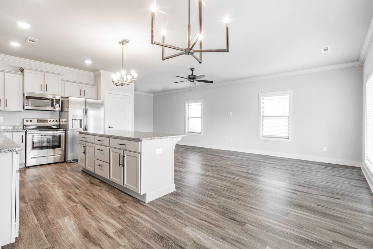 Open-concept kitchen and living room with gray cabinets, stainless steel appliances, and wood-look flooring.