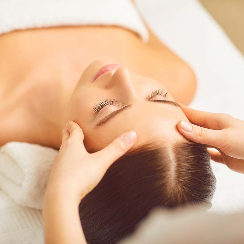 A woman is getting a head massage with her eyes closed