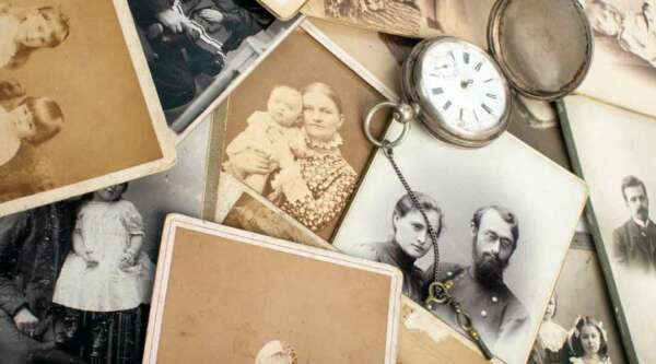 A pile of old photographs and a pocket watch.