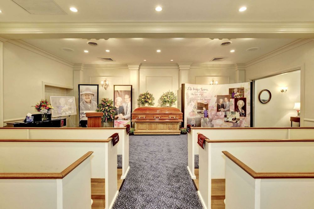 A funeral home with a coffin in the middle of the room.