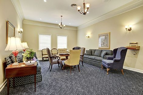 A living room with a couch , chairs , table and lamps.