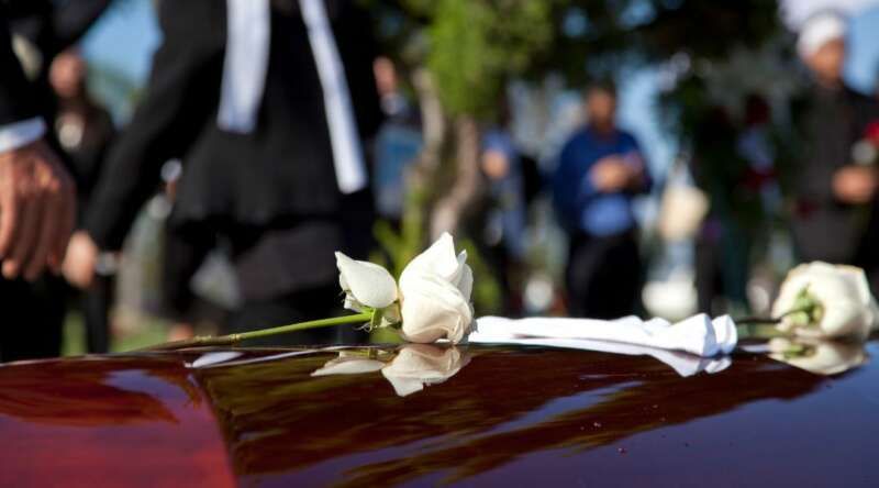 A white rose is sitting on the hood of a funeral car.