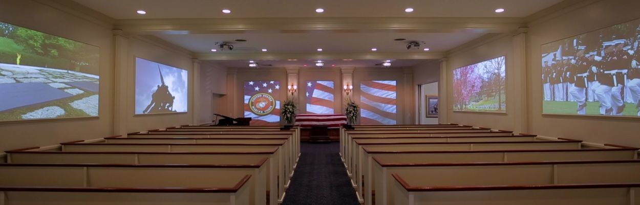 A church with rows of pews and a projector screen on the wall.