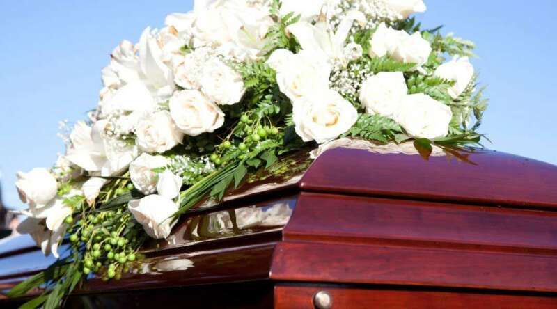 A wooden coffin with white flowers on top of it.