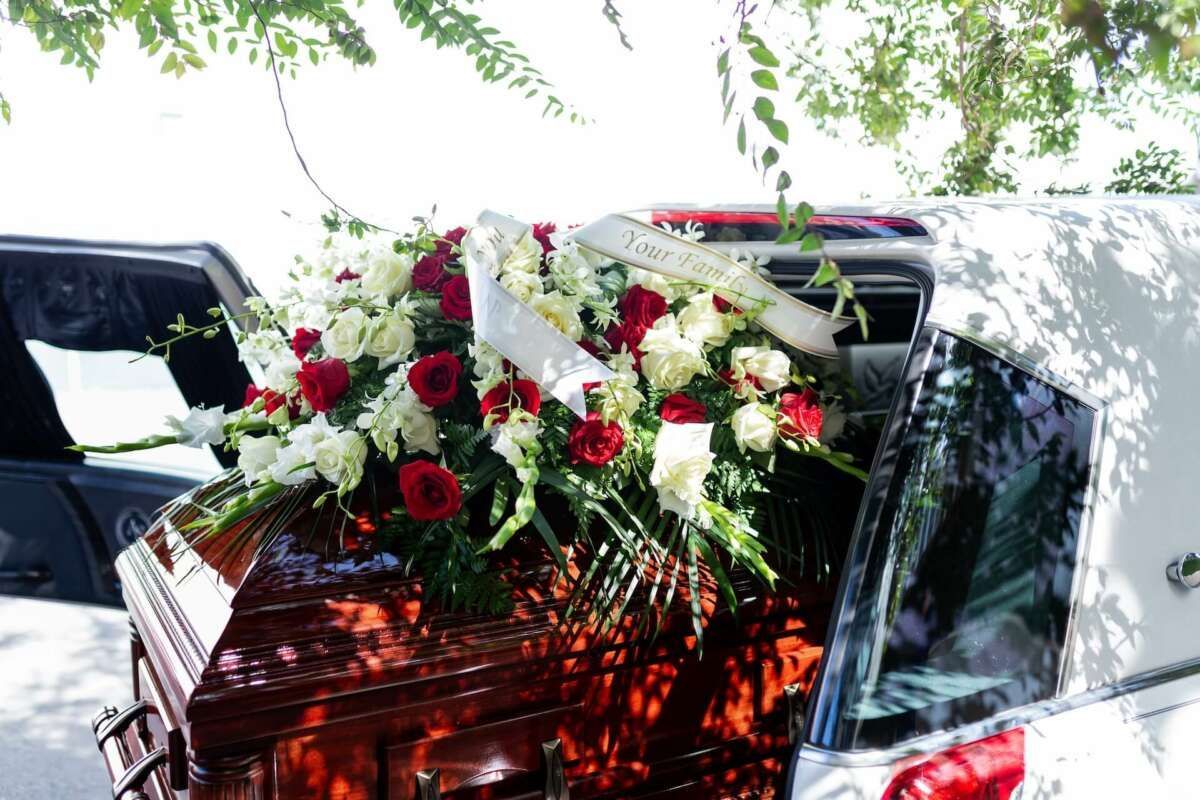A coffin with flowers on top of it is in a limousine.