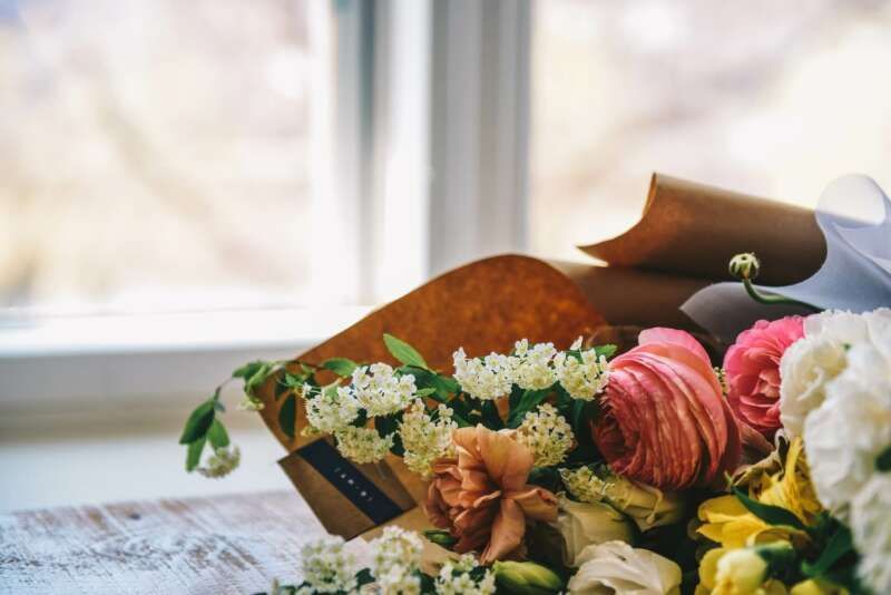 A bouquet of flowers is sitting on a table in front of a window.