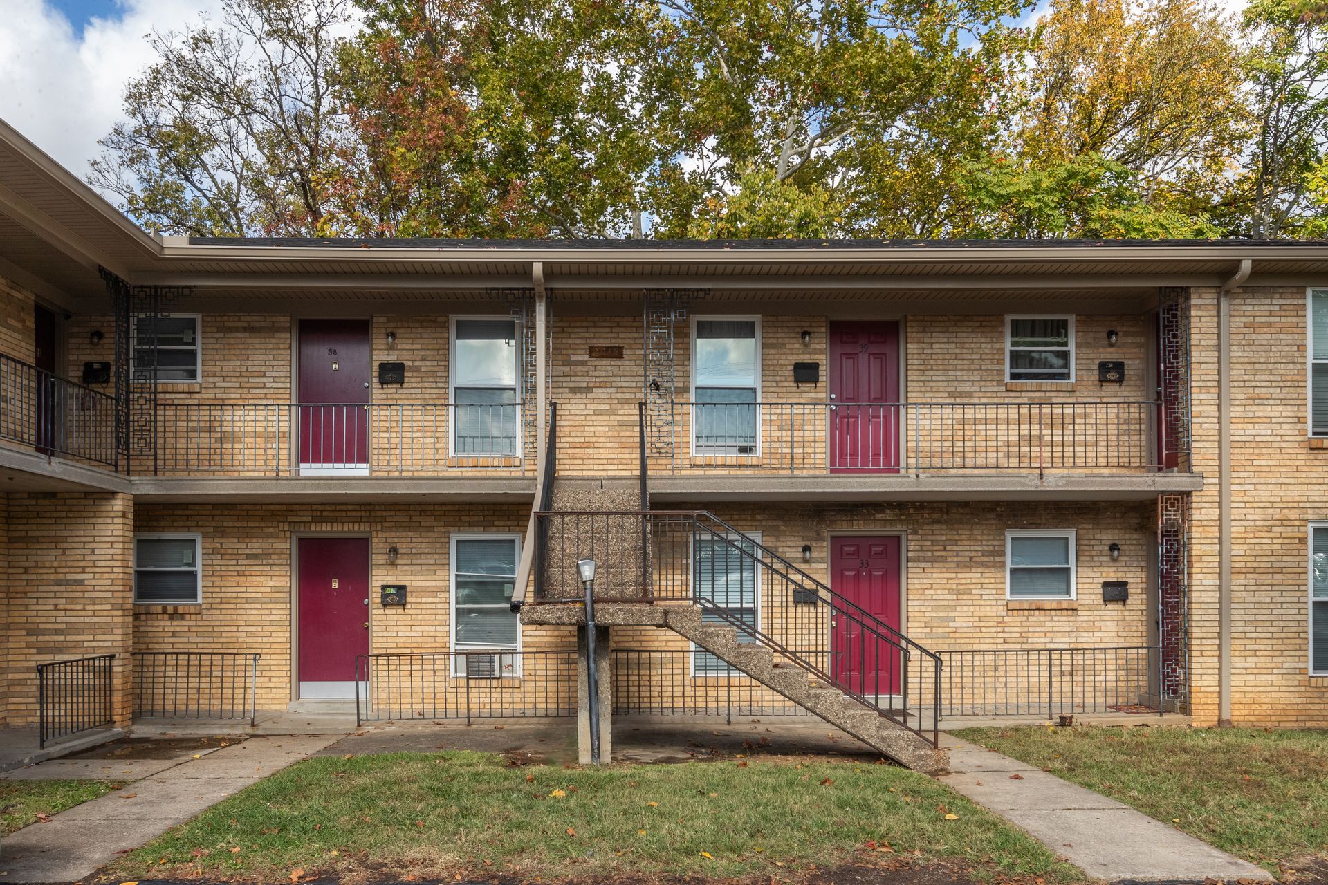 A brick apartment building with red doors and stairs