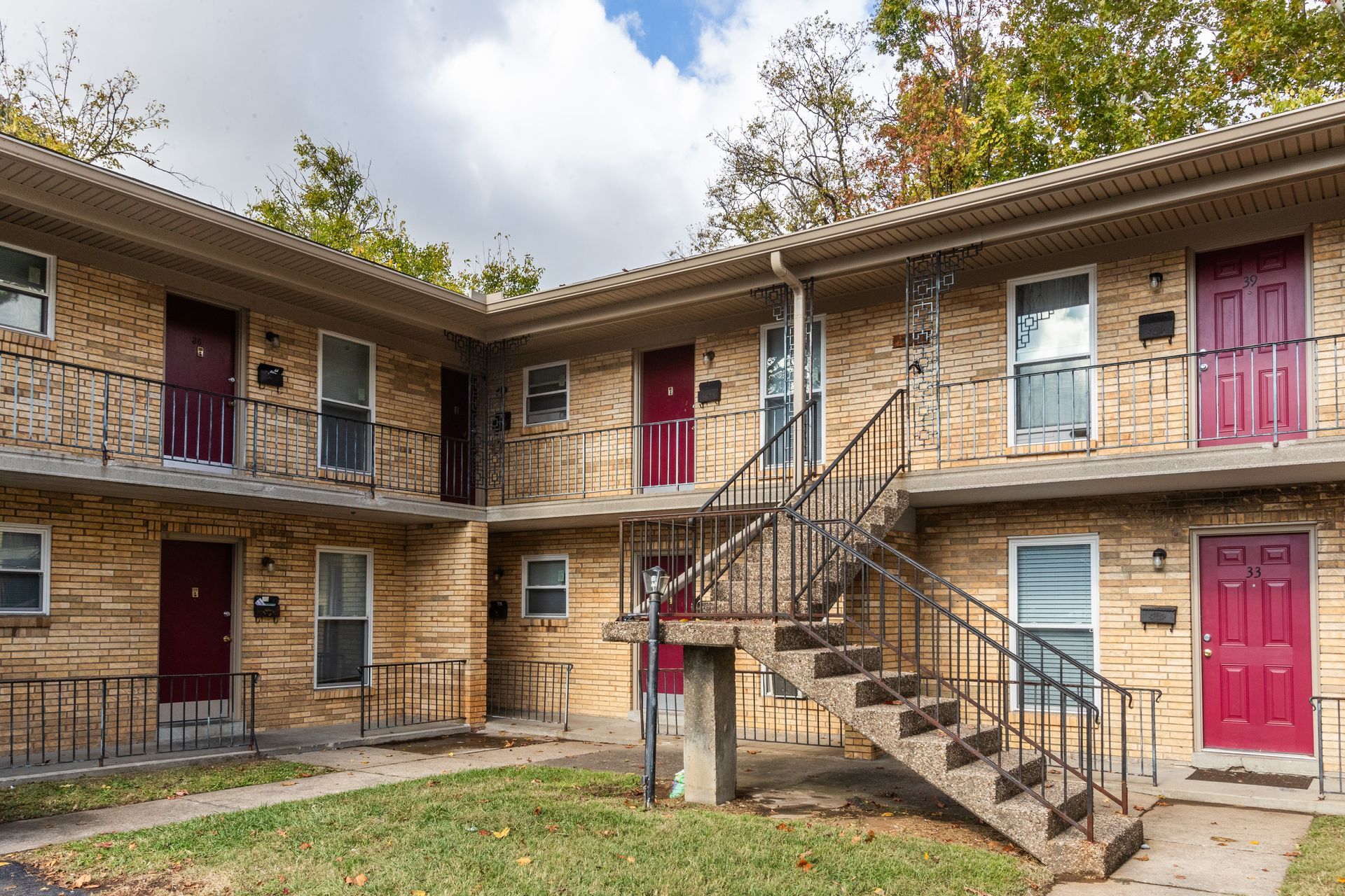 A brick apartment building with red doors and stairs.