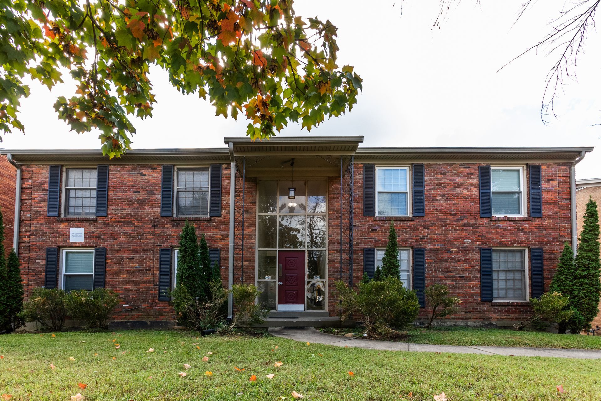 A brick apartment building with blue shutters and a red door.