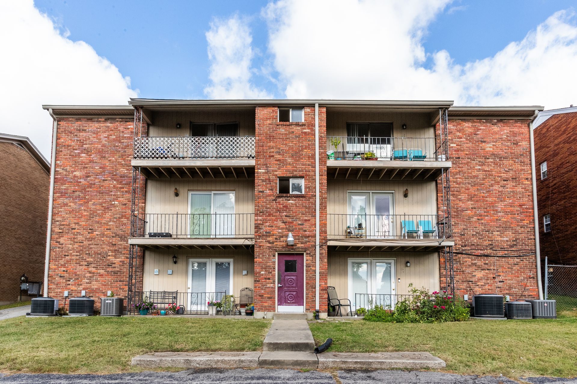 A large brick apartment building with a purple door and balconies.