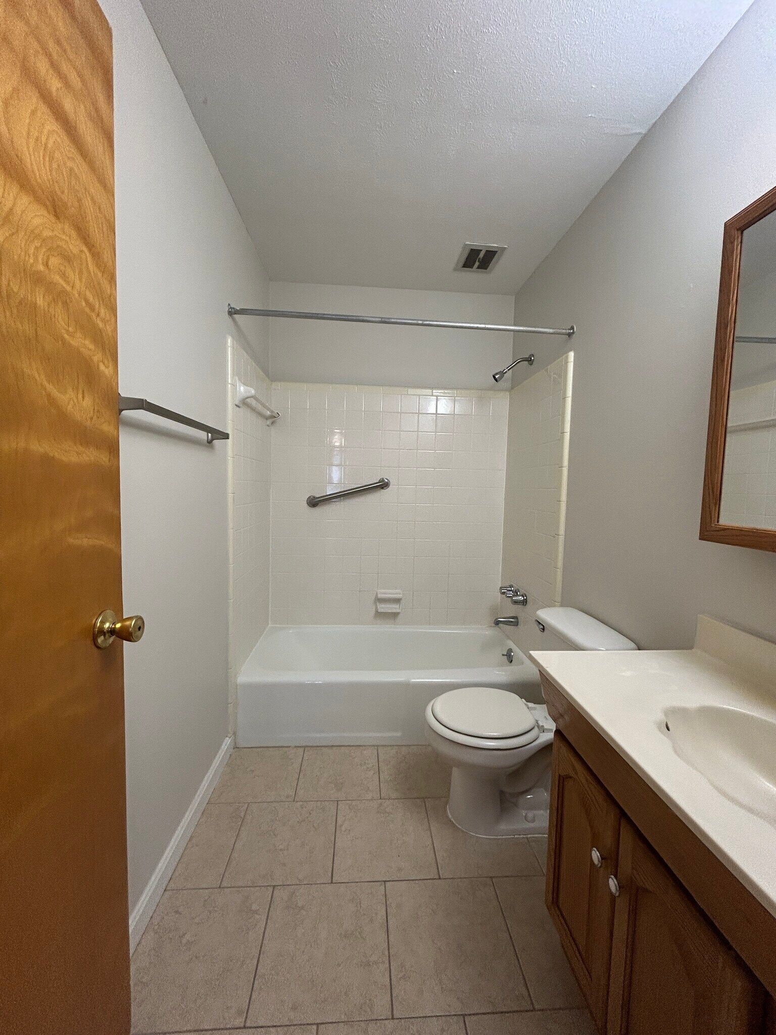 A bathroom with a tub , toilet , sink and mirror.