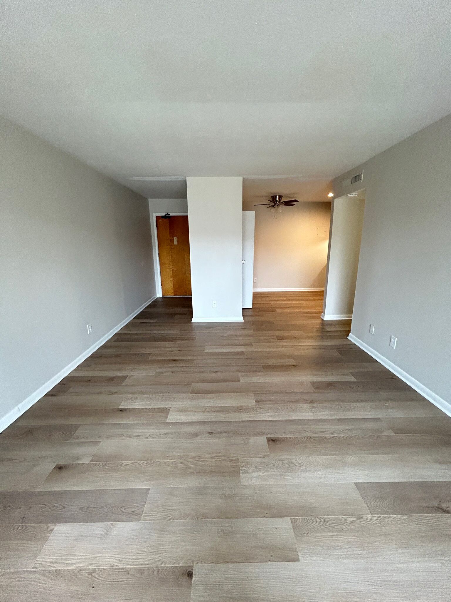 An empty living room with hardwood floors and a ceiling fan.