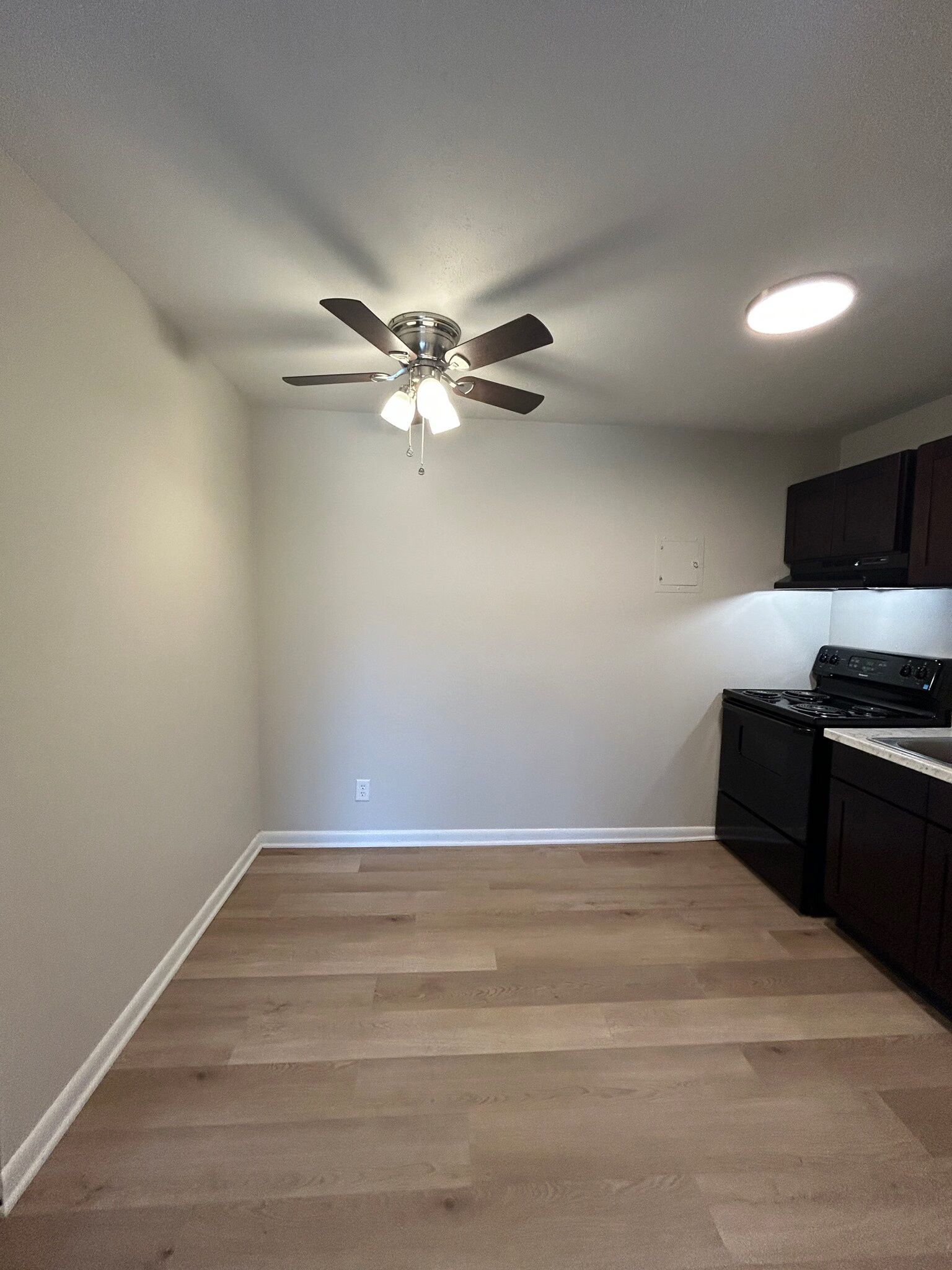 An empty kitchen with a ceiling fan and a stove.