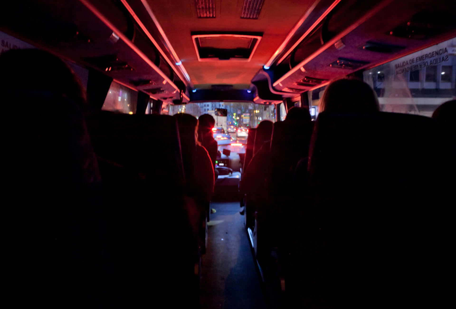 A group of people are sitting on a bus at night.