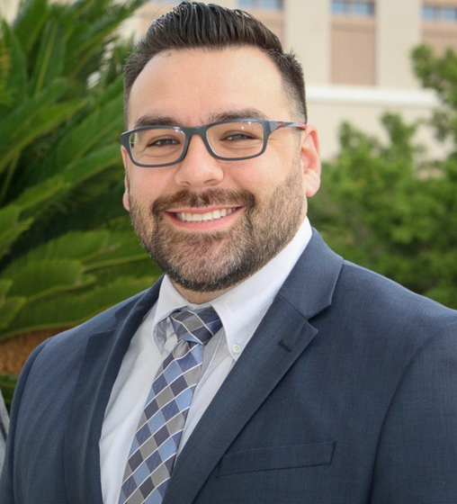 A man in a suit and tie is smiling for the camera