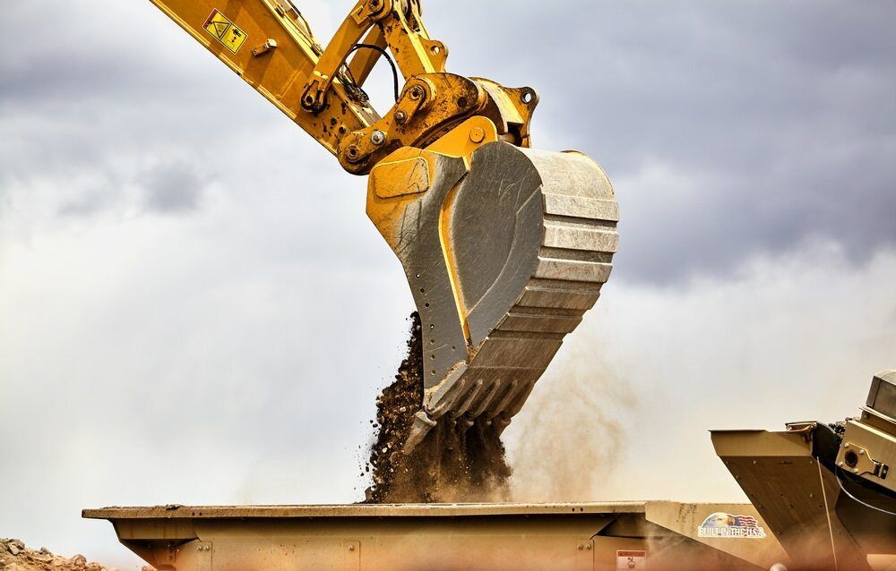 Yellow Excavator Dumping Dirt Into a Container — Marlborough Quarry (QLD) In Marlborough, QLD