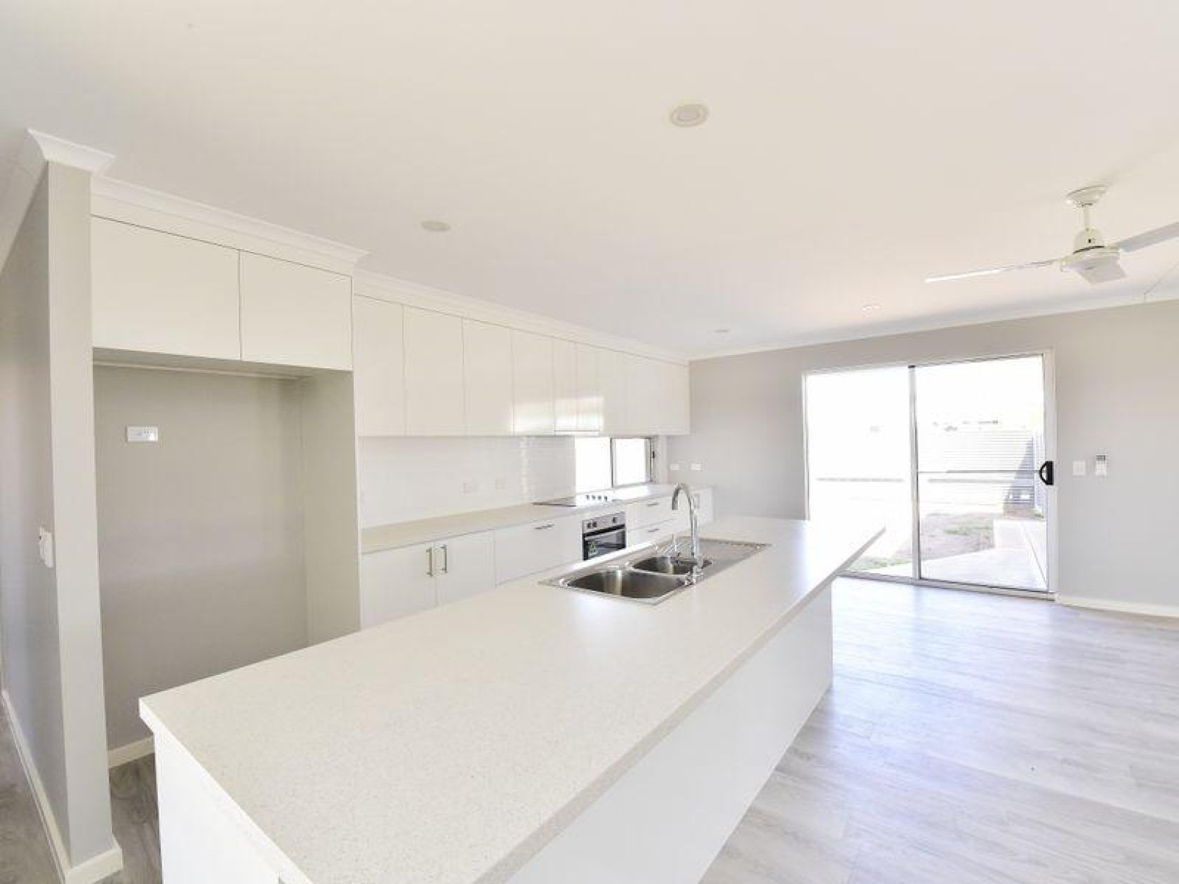 Modern kitchen with white cabinets, island, and sliding glass door.