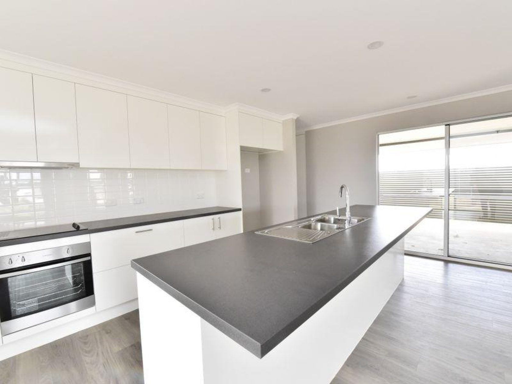 Modern white kitchen with gray countertop island and stainless steel appliances.