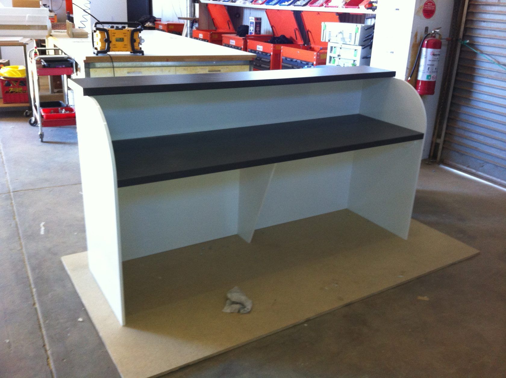 White and black counter in a workshop, with shelving.