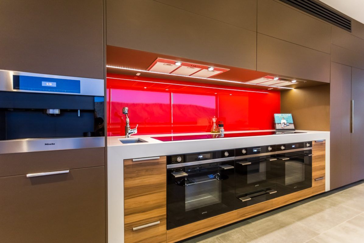 Modern kitchen with red backsplash, stainless steel appliances, and wood accents.