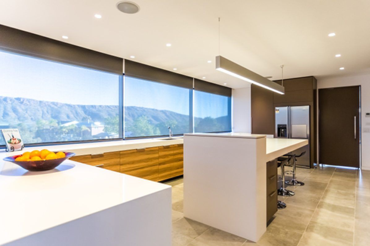 Modern kitchen with large windows, island, cabinetry, and a mountain view.