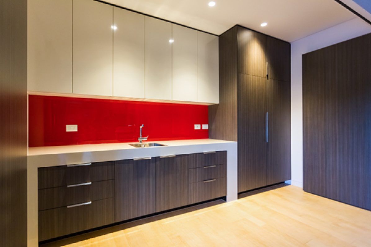 Modern kitchen with red backsplash, gray and dark brown cabinets, and a sink.