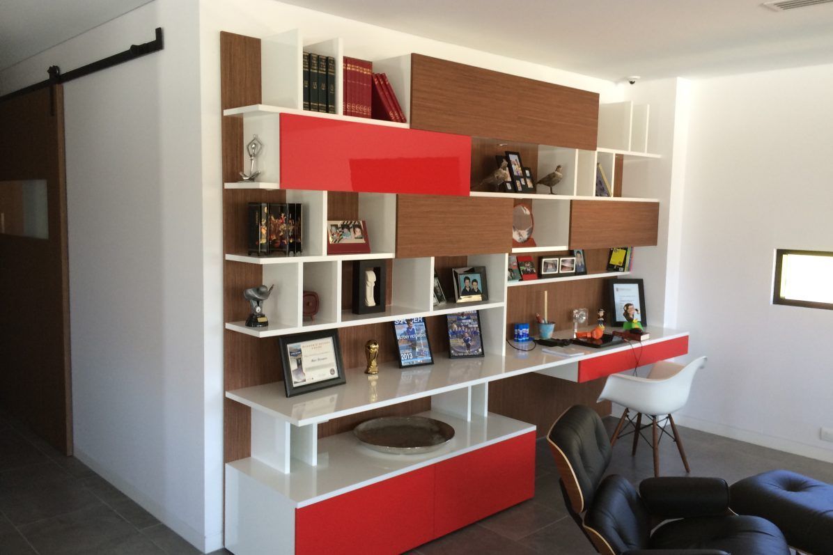 Modern office shelving with desk, red and white accents, and decorative items.